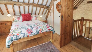 Une chambre à coucher au style rustique, avec un plafond en bois, une couvre-lit à motifs floraux et une porte en bois.