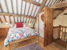 Quarto rústico com teto de madeira, colcha floral e porta de madeira.