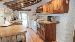 Une cuisine rustique avec des meubles en bois, un four à micro-ondes et une bouilloire.