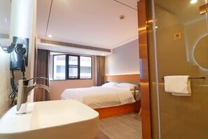 Habitación de hotel con una bañera grande, una cama con ropa blanca, una ventana con cortinas y un box de ducha de vidrio.