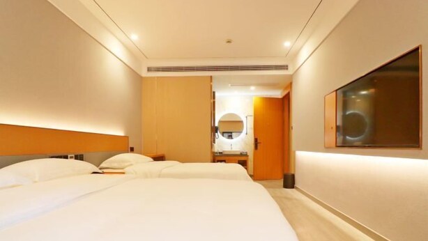 Een hotelkamer met een groot bed, een nachtkastje, een spiegel en een deur naar een badkamer.