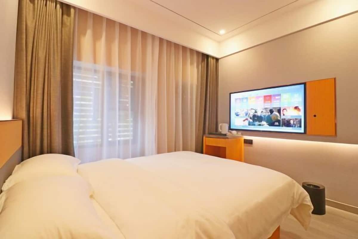 A hotel room with a bed, curtains, a television, and a small table.