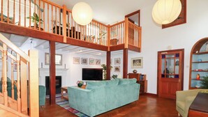 Un salon spacieux doté d’un parquet en bois à motifs chevrons, d’un canapé de couleur turquoise, d’un escalier en bois et d’une cheminée.