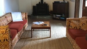 Ein gemütliches Wohnzimmer mit Kamin, gestreiften Sofas, einem Couchtisch und einem Fernseher.