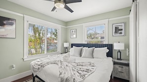 A bedroom with a bed, nightstands, a ceiling fan, and two windows with blinds. - Mins to Belmont Shore - Firepit - Game Room - BBQ - Free Parking - FIFA 2026! (Long Beach)