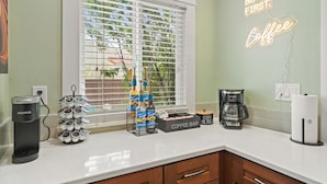 A kitchen with a coffee maker, a coffee bar, and a neon sign that reads "BUT FIRST Coffee". - Mins to Belmont Shore - Firepit - Game Room - BBQ - Free Parking - FIFA 2026! (Long Beach)