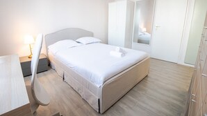 A neatly arranged bedroom with a bed, bedside table, lamp, wardrobe, and a mirror. - Le Tribut - with car park (Tours)