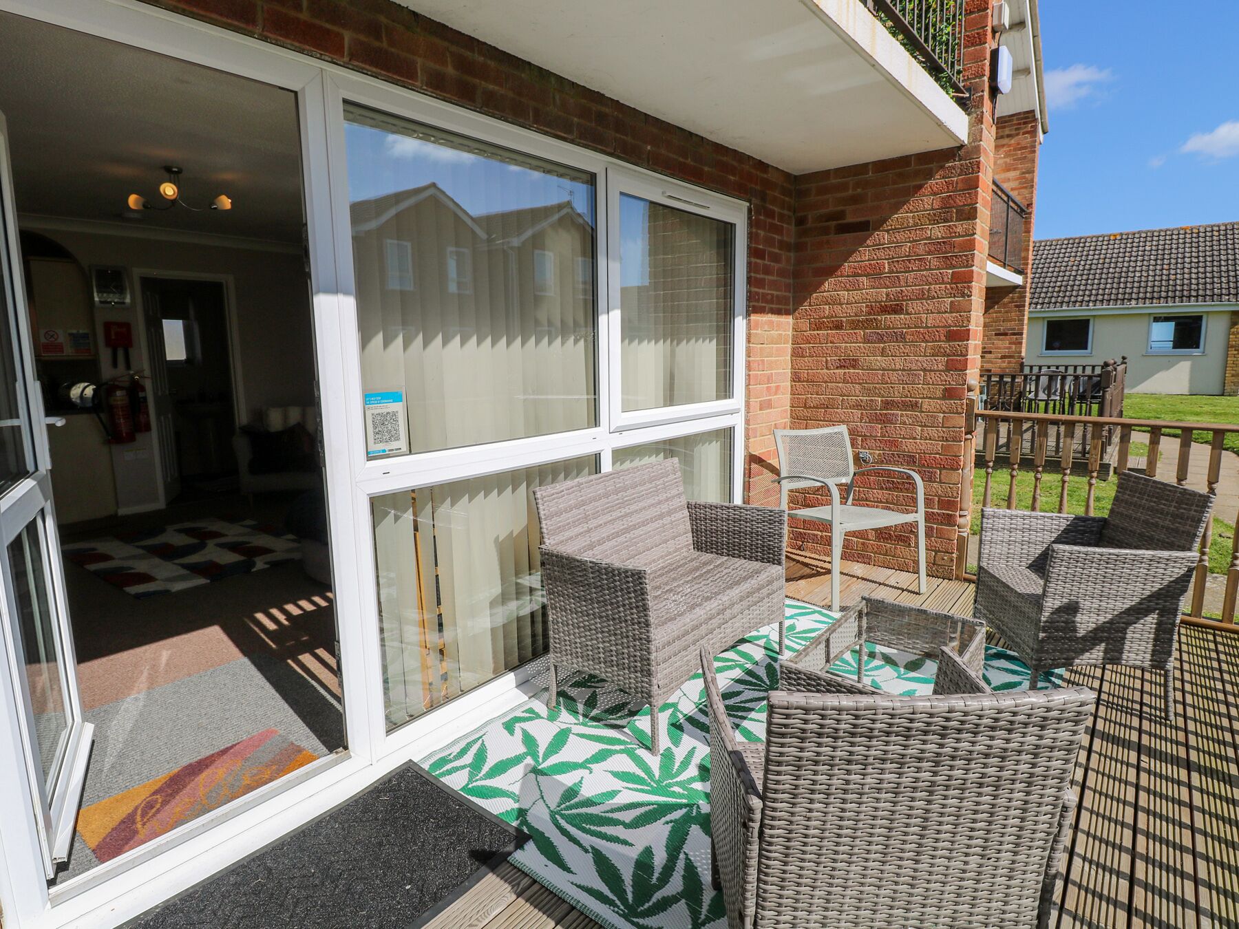 A balcony with wicker furniture and a view of neighboring houses.