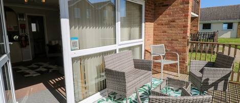 A balcony with wicker furniture and a view of neighboring houses.