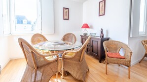 Un coin repas avec des chaises en osier, une table en verre et un meuble agrémenté d’une lampe.