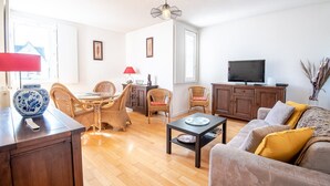 Un salon avec un plancher en bois, une table à manger avec des chaises, un canapé, un téléviseur et un meuble.
