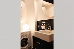 A compact bathroom with a washing machine, a sink, and a mirror. - Cracow Fancy Brick #5 - Old Town (Kraków)
