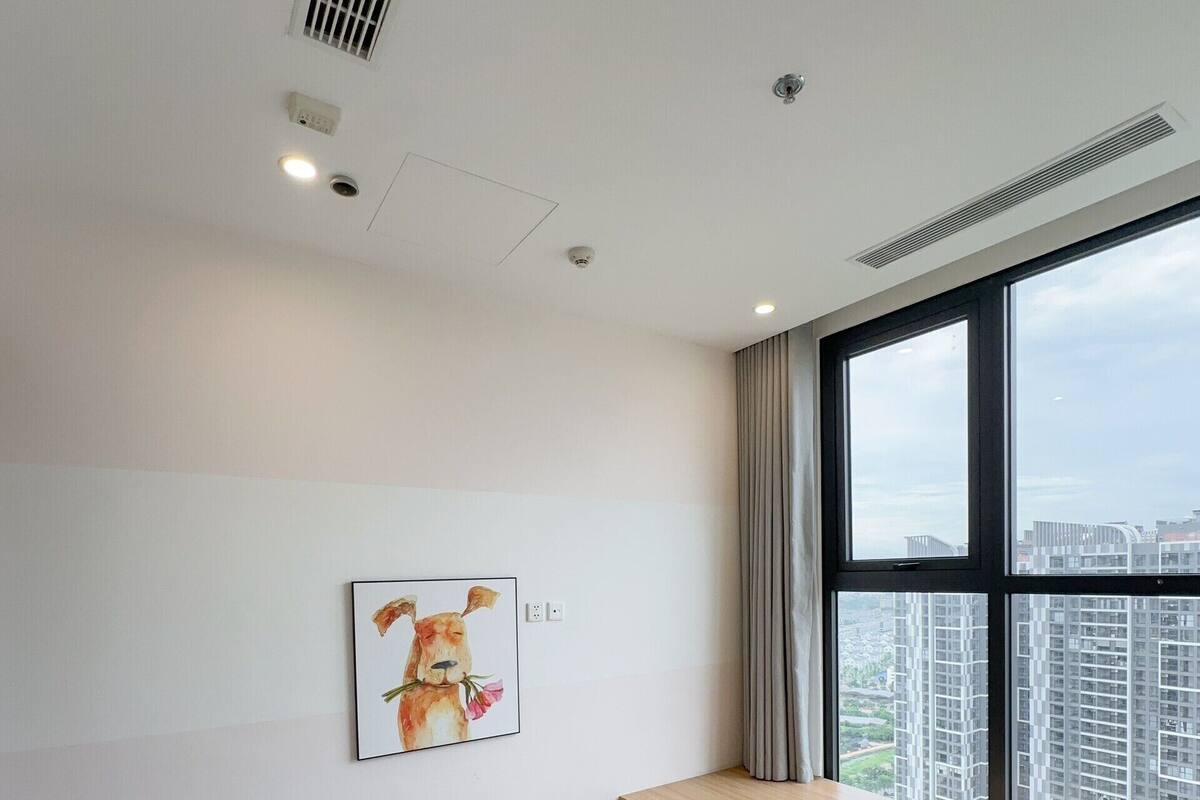 A modern hotel room with a large window, a bed, a staircase, and a painting on the wall.