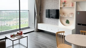 Una sala de estar moderna con un ventanal grande, un televisor de pantalla plana, un comedor y una cocina con electrodomésticos integrados.
