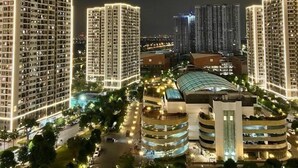 Complejo de edificios residenciales de gran altura en la noche, con ventanas iluminadas y una estructura central de estacionamiento.