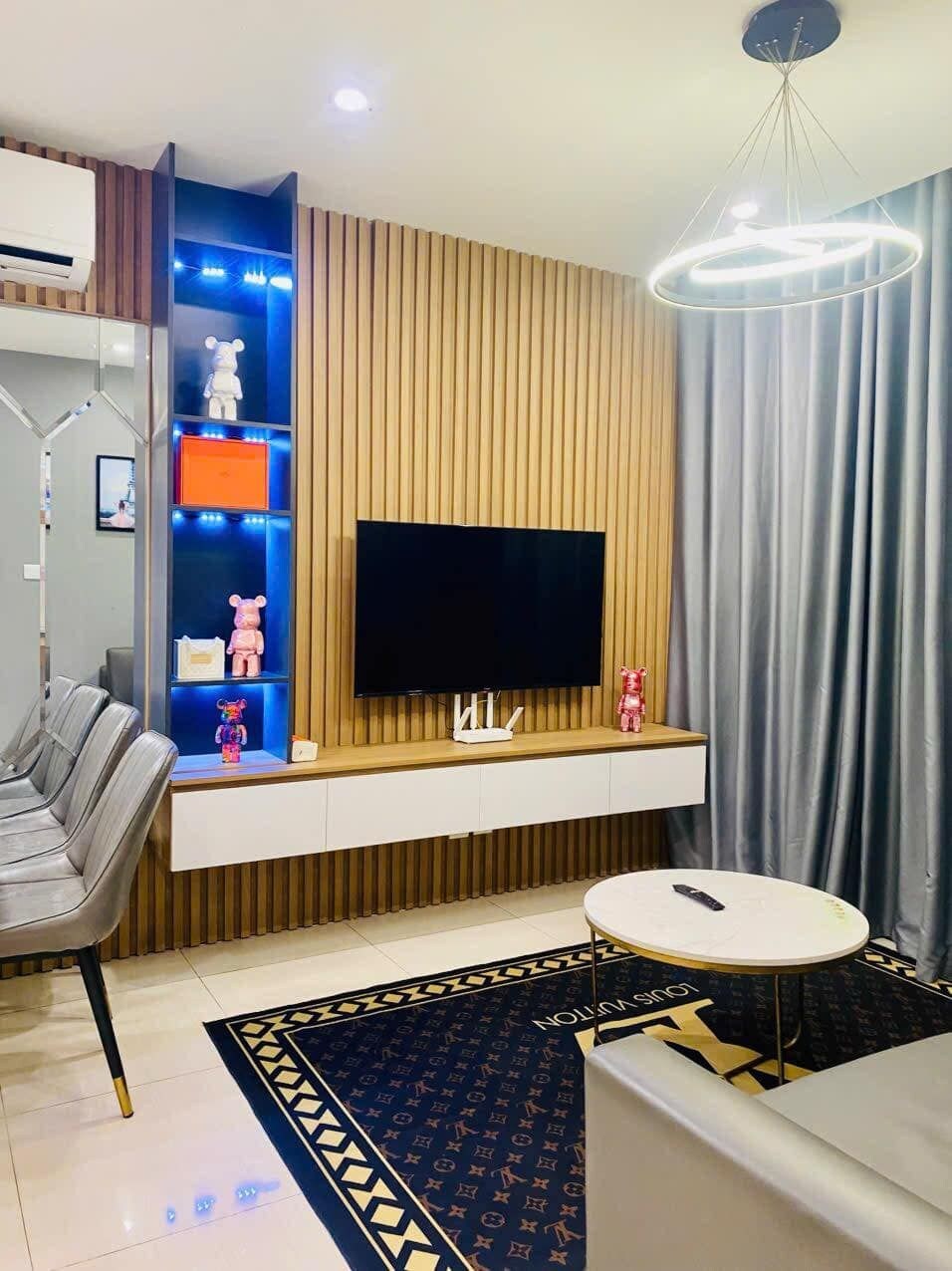 Una sala de estar moderna con un televisor de pantalla plana, un sofá blanco, una mesita redonda y una alfombra estampada.