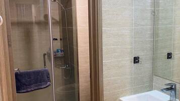 A modern bathroom with a glass-enclosed shower, a white sink, and a toilet.