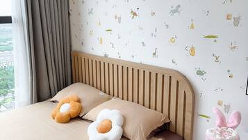 A bedroom with a bed, pillows, a nightstand, and a wall with alphabet and animal decals.