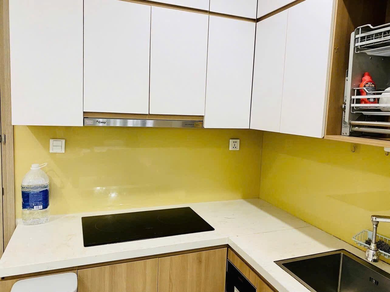 A kitchen with white cabinets, a yellow backsplash, a black countertop, and a sink.