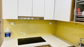 A kitchen with white cabinets, a yellow backsplash, a black countertop, and a sink.