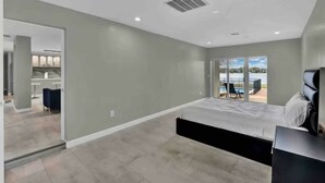 Un dormitorio moderno con una cama grande, un escritorio empotrado y vistas a una piscina.