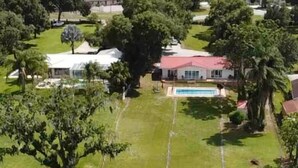 Un barrio residencial con un amplio césped, una piscina y un embarcadero que se adentra en un cuerpo de agua.
