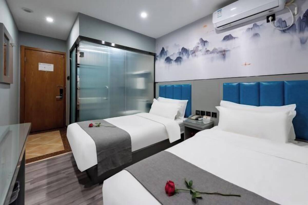 Quarto de hotel com duas camas, uma secretária e um banheiro.