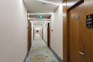 A hotel corridor with a carpeted floor, wooden doors, and a sign indicating room number 8309.