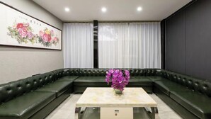 A modern living room with a sectional sofa, a glass coffee table, and a floral painting on the wall. - Super 8 (Beijing West Gongyi Bridge) (Beijing)