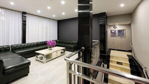 A modern living room with a black leather sofa, a wooden coffee table, and a staircase leading to an upper floor. - Super 8 (Beijing West Gongyi Bridge) (Beijing)