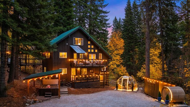 A wooden cabin with a balcony, surrounded by trees. - Forest+Mountain Views, Hot Tub, Sauna, EV Charger, Dogs OK, Near Lake Wenatchee (Leavenworth)