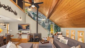 A spacious living room with a gray sofa, a fireplace, and a wooden ceiling. - Forest+Mountain Views, Hot Tub, Sauna, EV Charger, Dogs OK, Near Lake Wenatchee (Leavenworth)
