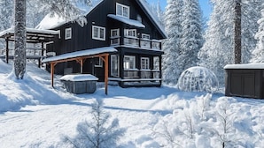 A two-story lodge with a balcony, surrounded by snow-covered trees. - Forest+Mountain Views, Hot Tub, Sauna, EV Charger, Dogs OK, Near Lake Wenatchee (Leavenworth)