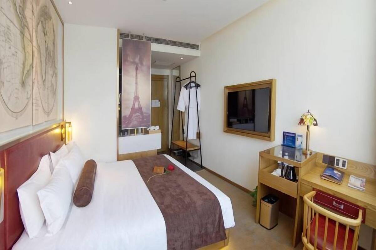 Habitación de hotel con cama, mesita de noche, lámpara y espejo.