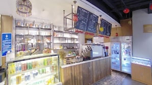 A cafe with a wooden counter, refrigerated display cases, and a menu board. - James Joyce Coffetel (Beijing Yizhuang East Rongjing Street Metro Station) (Beijing)
