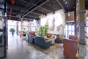 A spacious lobby with seating areas, a large wall-mounted artwork, and a visible staircase. - James Joyce Coffetel (Beijing Yizhuang East Rongjing Street Metro Station) (Beijing)