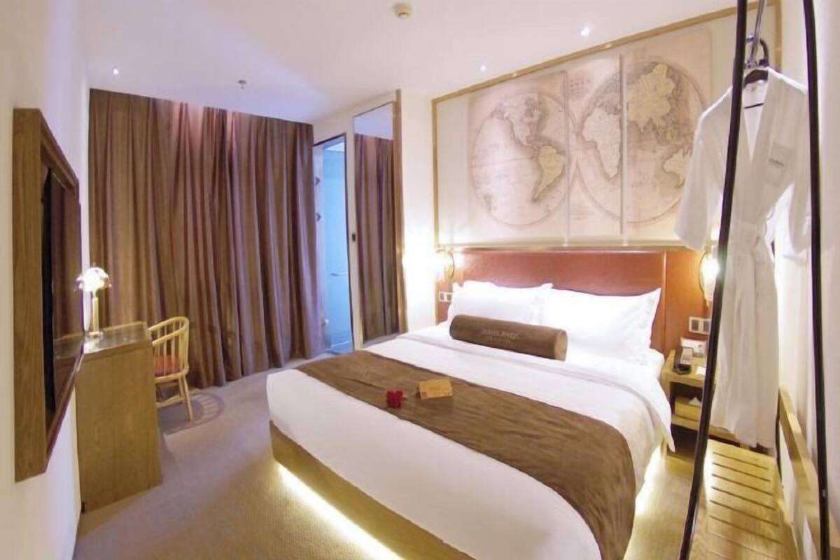 Habitación de hotel con una cama grande, un escritorio de madera, una silla, un mapa en la pared y una cortina.