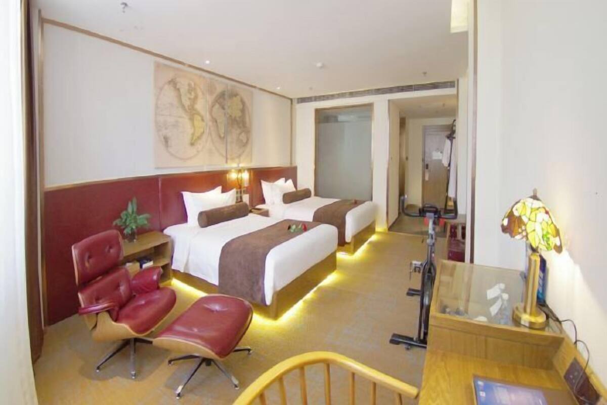 Una habitación de hotel con una cama, un escritorio, una silla y una lámpara.