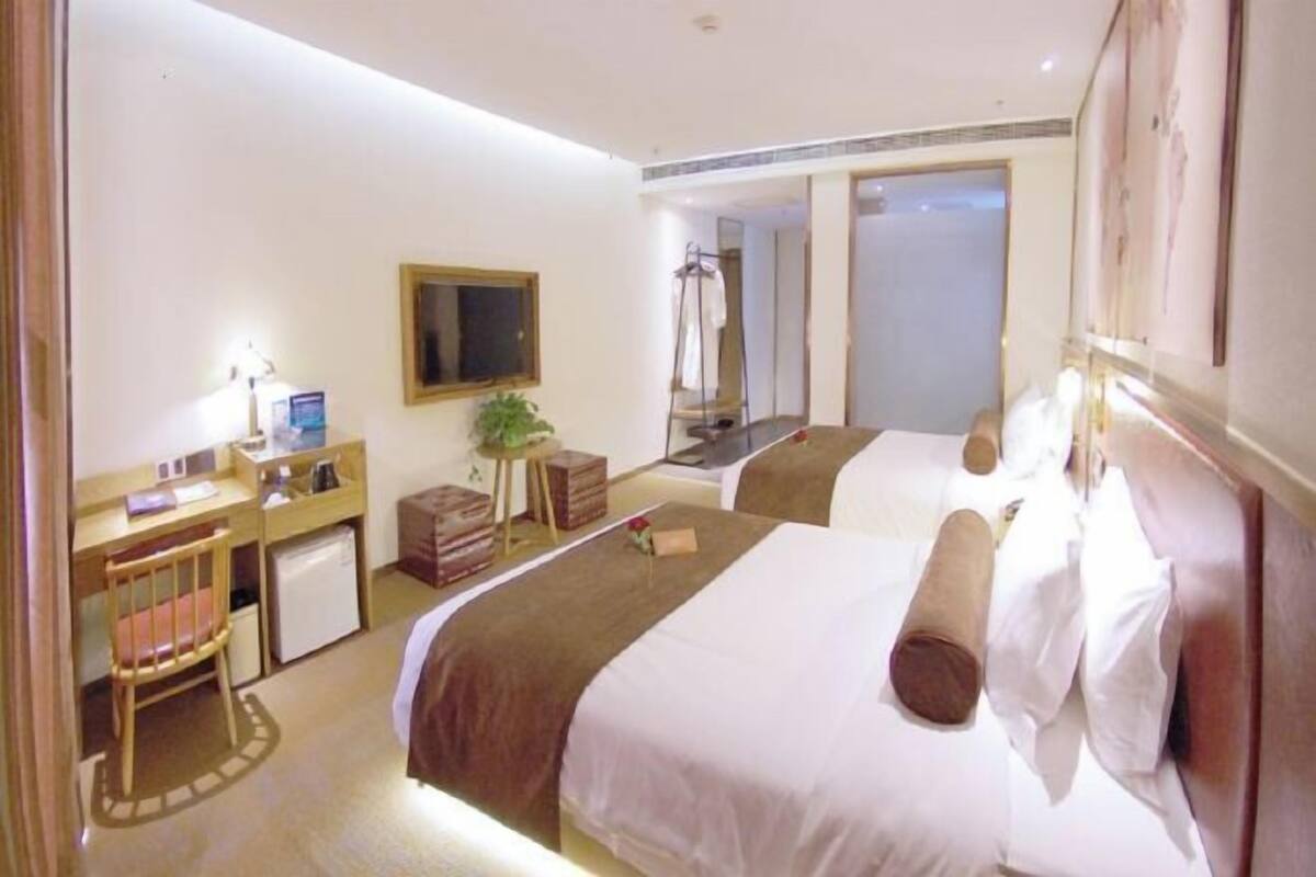 Una habitación de hotel con dos camas, un escritorio con silla, una mesita y un espejo.