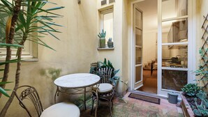 A patio with a table and chairs, a potted plant, and a door leading to an interior space. - Residenza Pinzochere (Firenze)