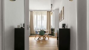 A modern interior with a wooden floor, a dining area with a table and chairs, and two clocks on the walls.