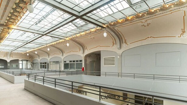 A spacious indoor area with a glass ceiling, multiple levels, and a railing.