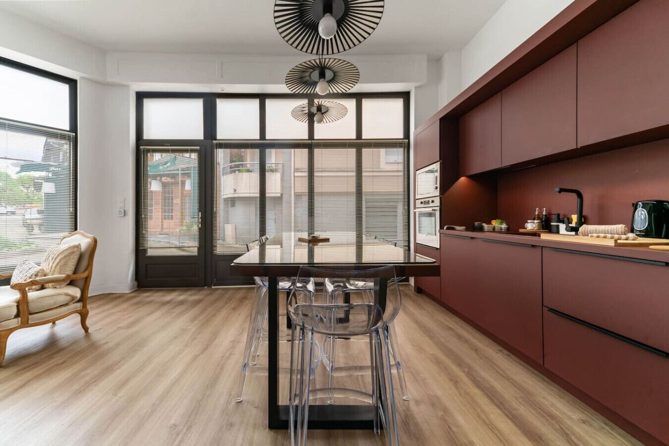 Une cuisine moderne avec un coin repas, dotée d’une grande fenêtre, d’un ventilateur et d’un plancher en bois.