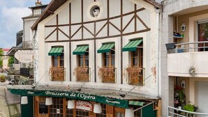 A building with a restaurant named "Brasserie de l'Opéra" featuring a traditional European architectural style with a balcony and green awnings. - Maison design hyper centre - Triangle d'or (Vichy)