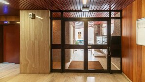 A hotel entrance with a wooden interior, a glass door, and a view of the street outside.