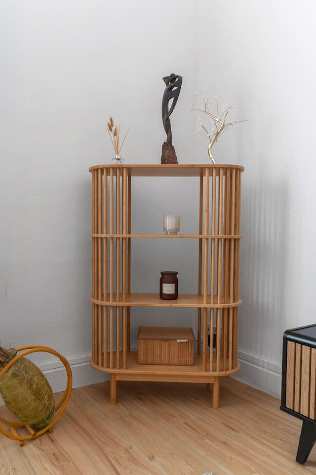 A wooden, multi-tiered bookcase with three shelves, a small decorative sculpture, and two vases.