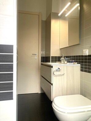 A modern bathroom with a toilet, a sink, and a mirror. - Lovely stay at Coronelli 7 (Milan)