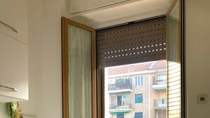 A modern apartment with a kitchen area, a dining table, and a balcony with a view of a residential building. - Lovely stay at Coronelli 7 (Milan)
