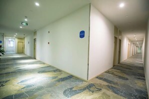 A long, narrow hotel corridor with a patterned carpet, doors on both sides, and a blue sign on the wall. - Weiting Qingju Hotel (Shanghai Hongqiao Airport Beihua Road Branch) (Shanghai)