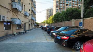 Una calle estrecha flanqueada por coches aparcados y edificios de varios pisos con balcones.